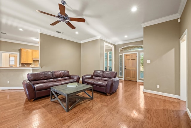 living room with light hardwood / wood-style floors, ceiling fan, and crown molding