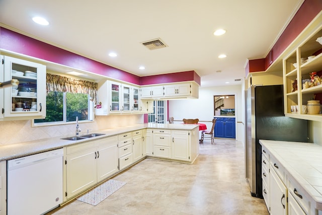 kitchen with stainless steel fridge, backsplash, white dishwasher, sink, and kitchen peninsula