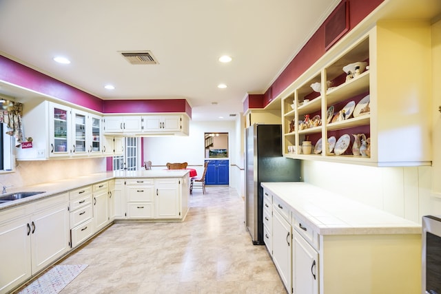 kitchen featuring white cabinets, kitchen peninsula, and stainless steel fridge