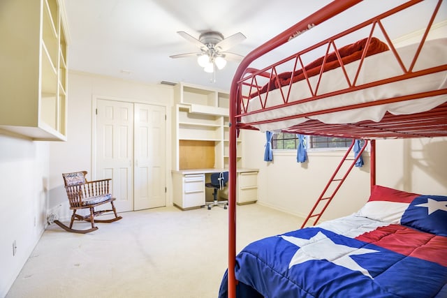 carpeted bedroom featuring a closet, built in desk, and ceiling fan