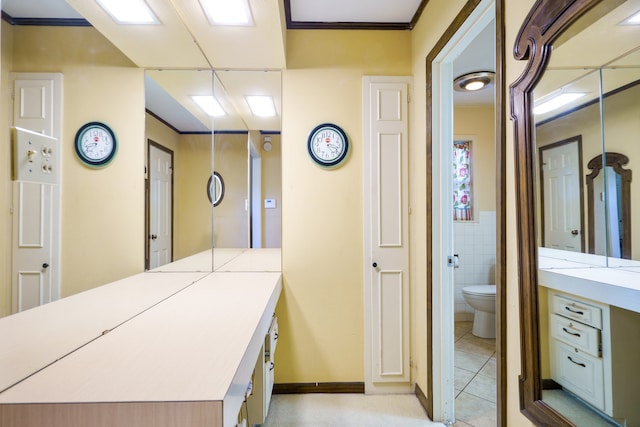 bathroom with tile patterned flooring, toilet, tile walls, and ornamental molding