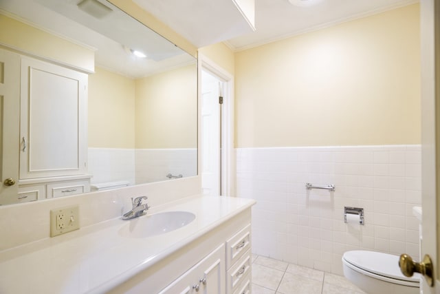 bathroom with toilet, tile patterned floors, tile walls, ornamental molding, and vanity