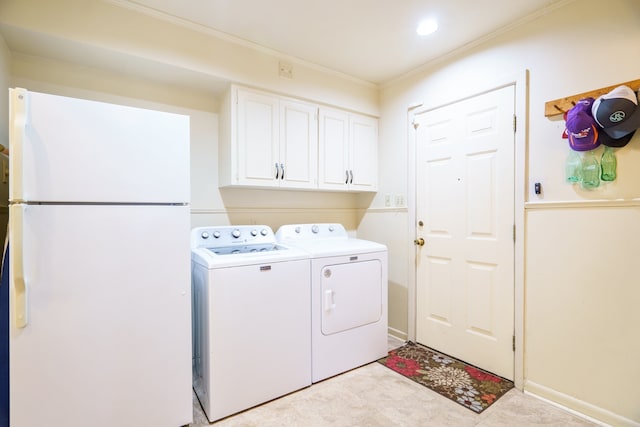 clothes washing area featuring cabinets, crown molding, and washer and dryer