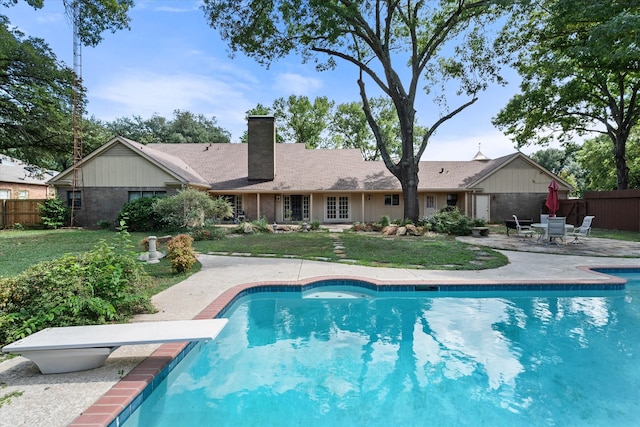 view of pool featuring a diving board, a lawn, and a patio area