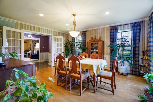 dining area with light wood-type flooring, crown molding, and an inviting chandelier