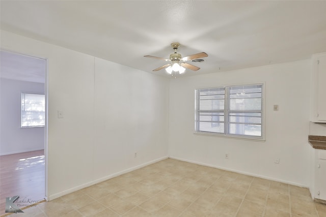 unfurnished room featuring a healthy amount of sunlight and ceiling fan