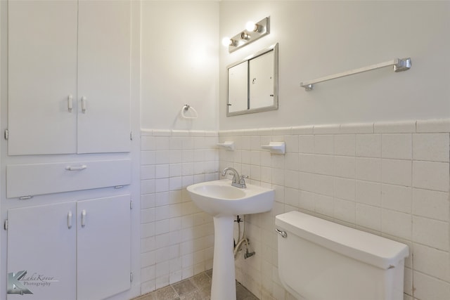 bathroom with toilet, tile walls, sink, and tile patterned flooring