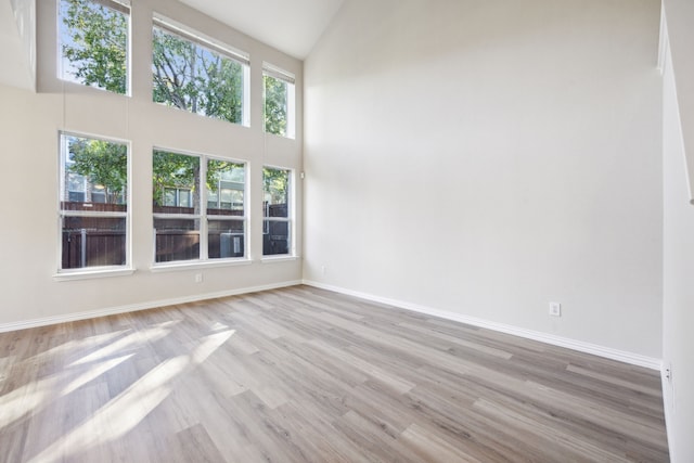 spare room featuring high vaulted ceiling and light wood-type flooring