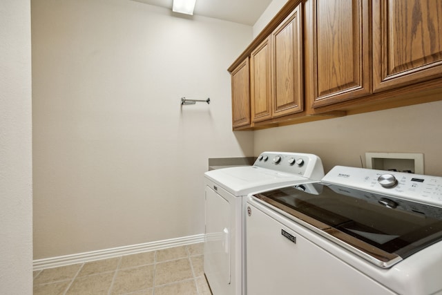 clothes washing area with cabinets, light tile patterned flooring, and washer and dryer