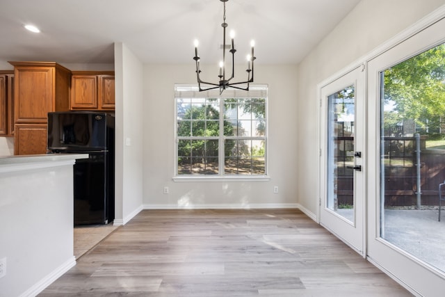 kitchen with black fridge, hanging light fixtures, light hardwood / wood-style floors, and a chandelier