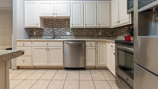 kitchen with decorative backsplash, light tile patterned flooring, sink, and stainless steel appliances