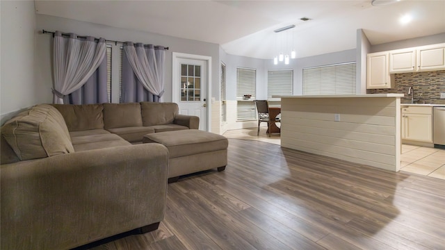 living room featuring lofted ceiling, sink, and light hardwood / wood-style floors