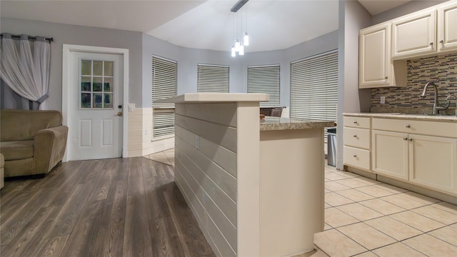 kitchen featuring backsplash, sink, light hardwood / wood-style flooring, a chandelier, and hanging light fixtures