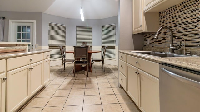 kitchen with sink, stainless steel dishwasher, backsplash, pendant lighting, and light tile patterned floors