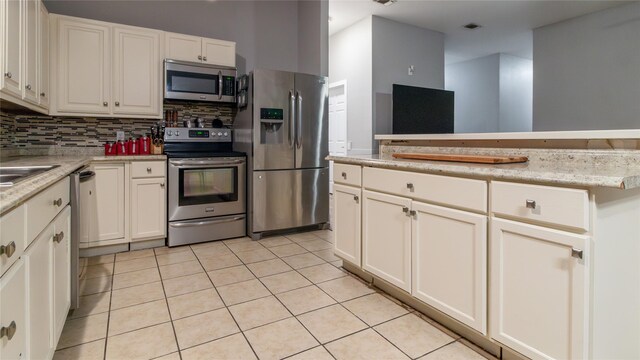 kitchen with white cabinets, decorative backsplash, light tile patterned floors, and stainless steel appliances