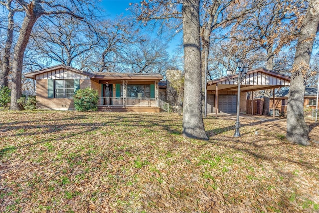 single story home featuring a carport, a garage, covered porch, and a front yard