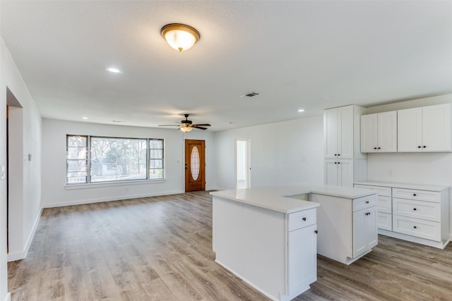 kitchen featuring ceiling fan, white cabinets, light wood-type flooring, and a kitchen island