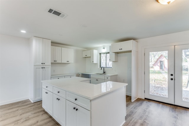 kitchen featuring light hardwood / wood-style flooring, white cabinetry, sink, and french doors