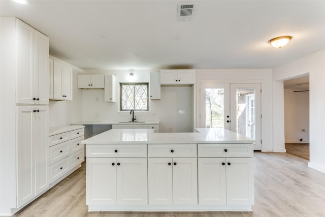 kitchen with white cabinetry, sink, and a kitchen island