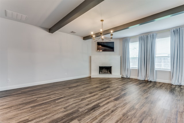 unfurnished living room with a fireplace, dark hardwood / wood-style flooring, beam ceiling, and an inviting chandelier