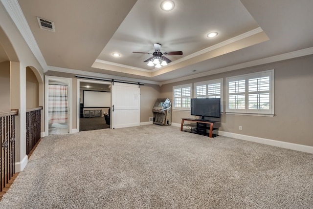 unfurnished living room with carpet, a barn door, a raised ceiling, and crown molding