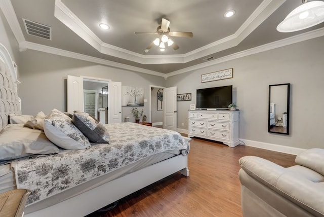 bedroom with a tray ceiling, ceiling fan, wood-type flooring, and ornamental molding