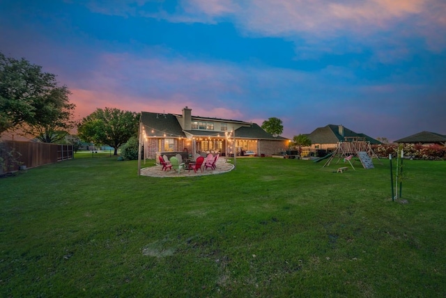 yard at dusk featuring a playground and a patio