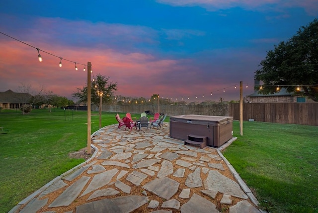 patio terrace at dusk with a yard and a hot tub