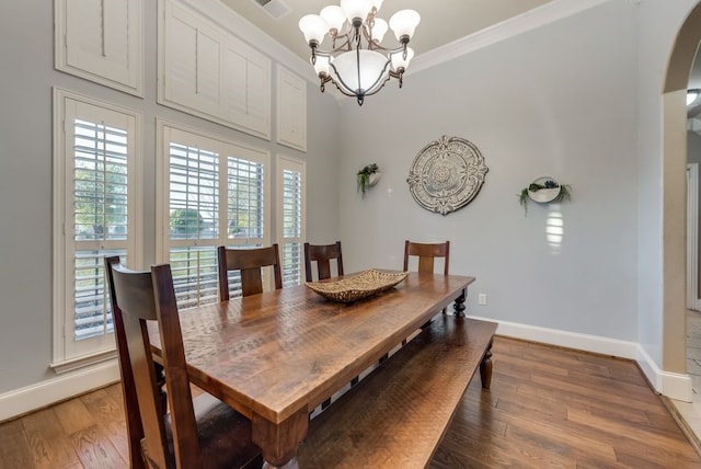 dining area with wood-type flooring, ornamental molding, and an inviting chandelier