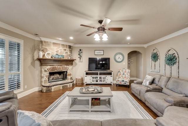 living room featuring a stone fireplace, crown molding, hardwood / wood-style floors, and ceiling fan