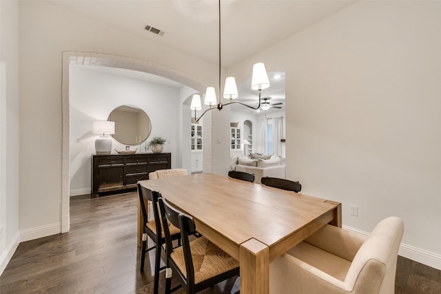 dining space with arched walkways, visible vents, a chandelier, and dark wood-style floors