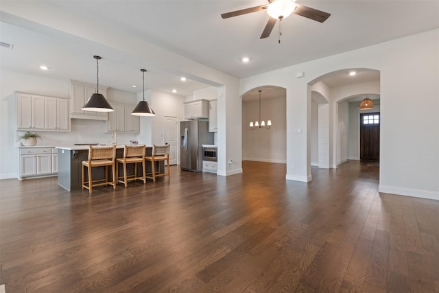 living area with visible vents, baseboards, dark wood finished floors, recessed lighting, and ceiling fan with notable chandelier