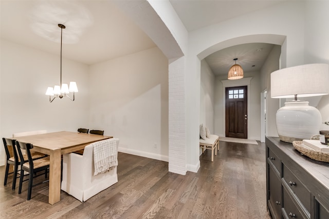 dining area with dark hardwood / wood-style floors and an inviting chandelier