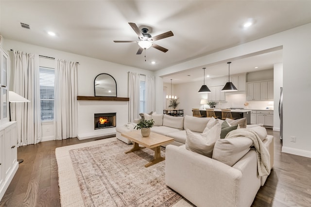 living room featuring dark wood-type flooring and ceiling fan with notable chandelier