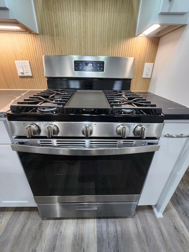 room details featuring white cabinets, wood-type flooring, and stainless steel gas range