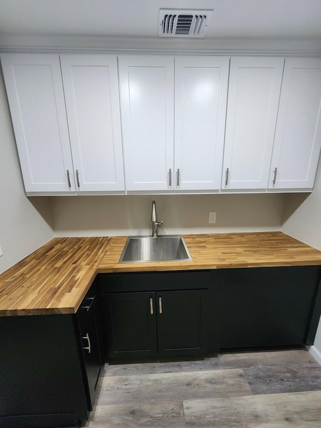 kitchen with white cabinets, light hardwood / wood-style floors, sink, and wooden counters