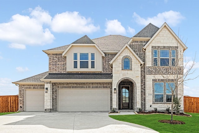 french country style house featuring fence, stone siding, driveway, roof with shingles, and a front yard