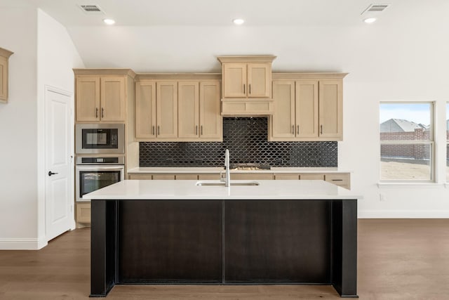 kitchen featuring visible vents, light brown cabinets, stainless steel oven, and built in microwave