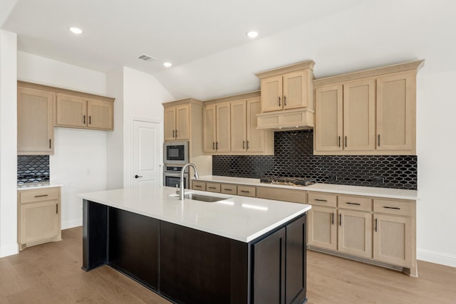 kitchen with light brown cabinets, premium range hood, a sink, visible vents, and appliances with stainless steel finishes