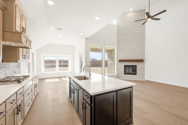 kitchen with open floor plan, light countertops, a fireplace, stainless steel gas cooktop, and a sink