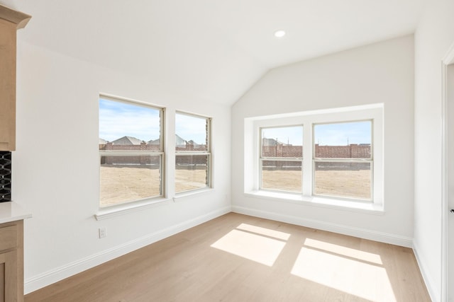 interior space featuring light wood-style floors, lofted ceiling, and baseboards