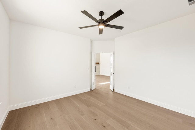 spare room with a ceiling fan, visible vents, light wood-style flooring, and baseboards