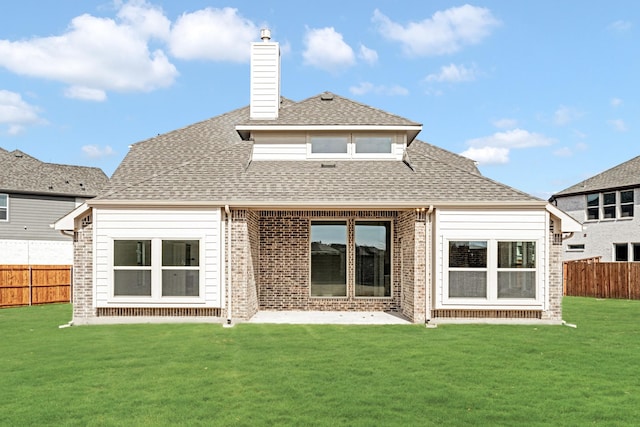 rear view of property featuring brick siding, a shingled roof, fence, a yard, and a chimney