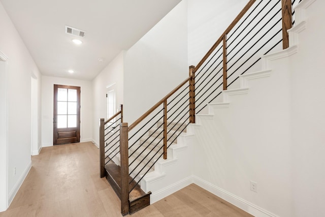 foyer entrance featuring baseboards, stairway, visible vents, and light wood-style floors