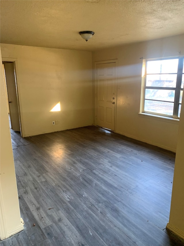 spare room featuring dark wood-type flooring and a textured ceiling