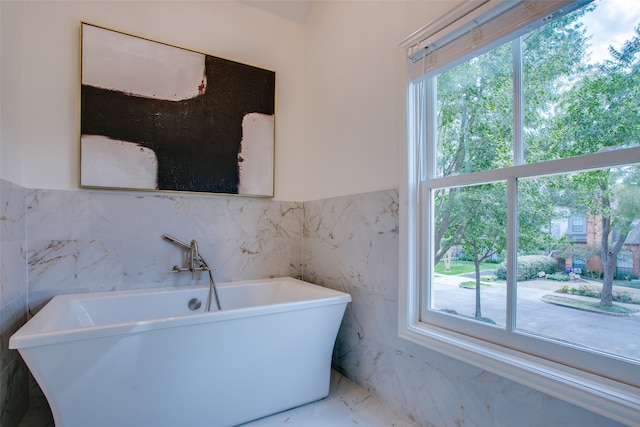 bathroom featuring tile walls, plenty of natural light, and a bath