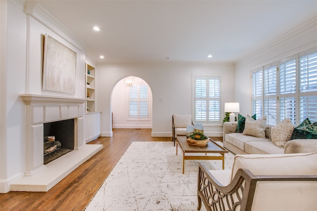 living room featuring ornamental molding, light hardwood / wood-style floors, and built in shelves