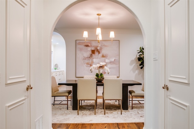 dining room featuring ornamental molding, a chandelier, and light hardwood / wood-style floors