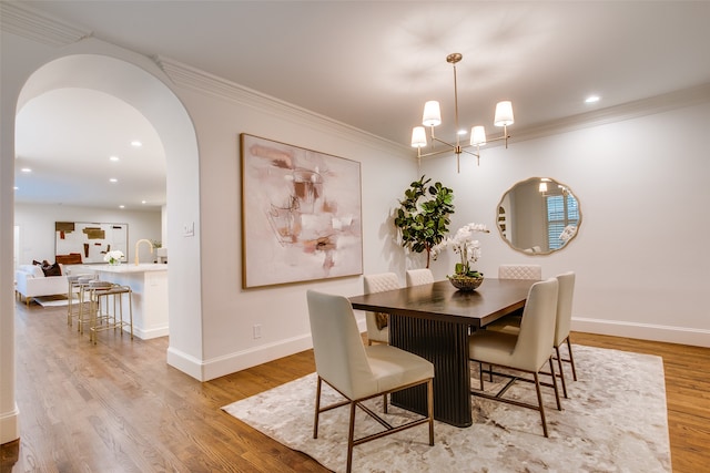 dining space with a chandelier, crown molding, and light hardwood / wood-style flooring