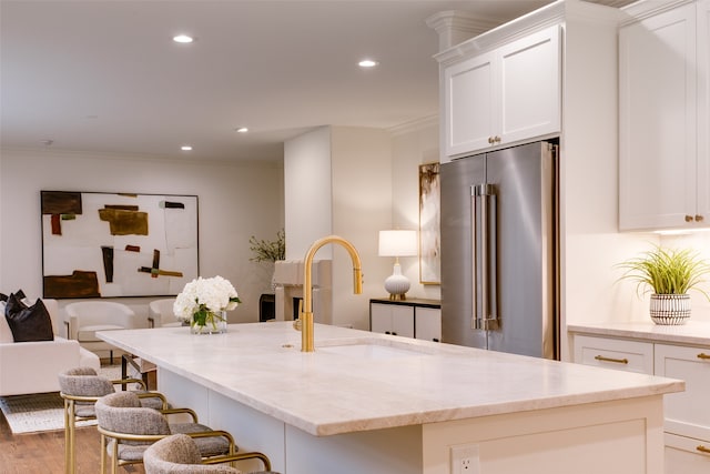 kitchen with white cabinets, high end fridge, wood-type flooring, and sink